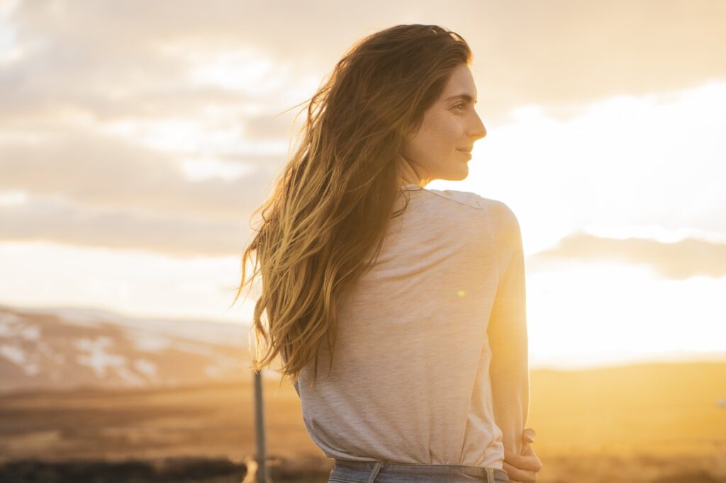 Iceland, young woman at sunset, rear view