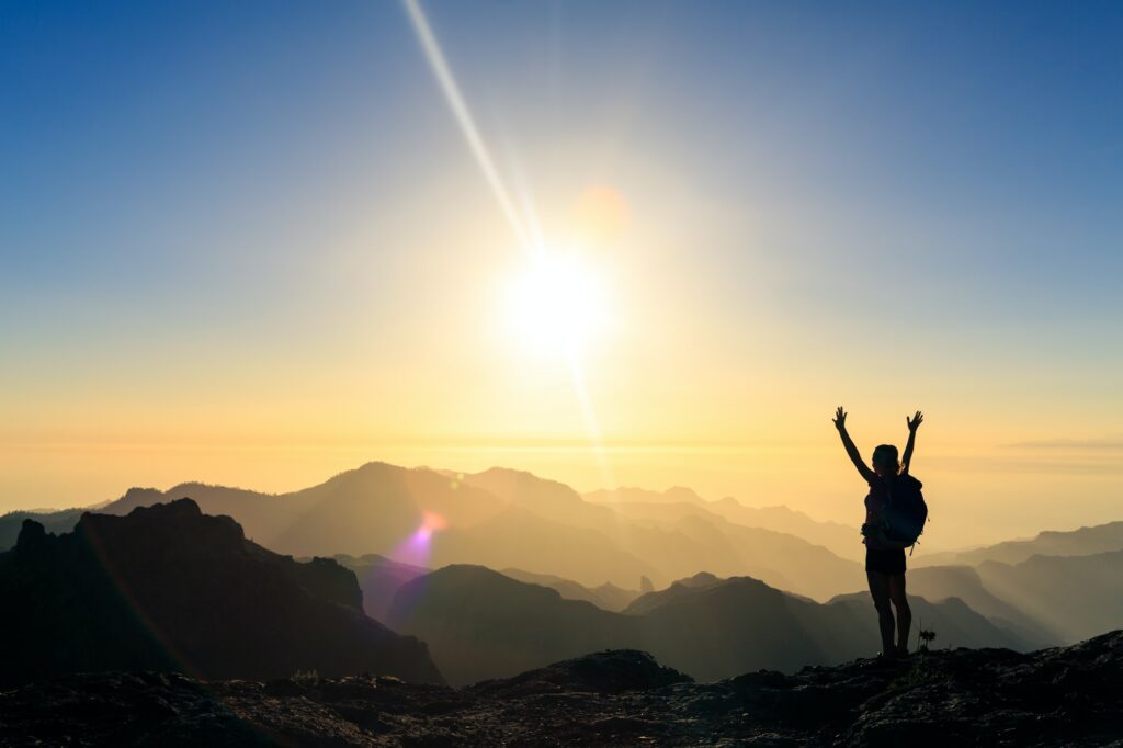 Woman hiking success silhouette in mountains sunset